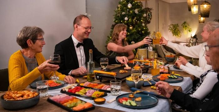 Familie rond een kersttafel die een Grillschotel eet