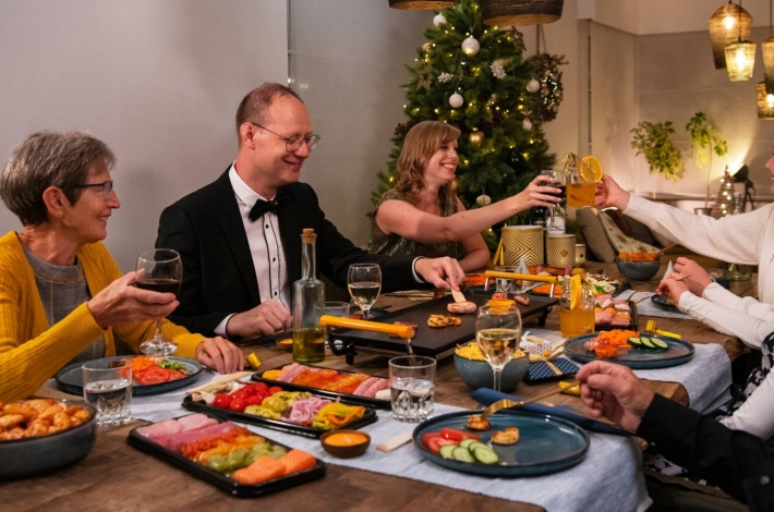 Familie rond een kersttafel die een Grillschotel eet